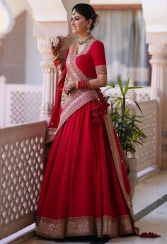 a woman in a red and gold bridal gown standing next to a planter