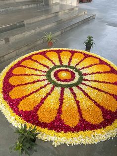 a large flower arrangement in the shape of an orange and yellow wheelbarrow on steps