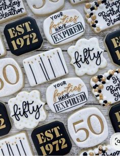 cookies decorated with black and white icing are displayed on a tablecloth that says 50th