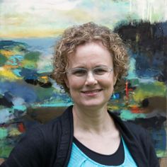 a woman wearing glasses standing in front of a painting