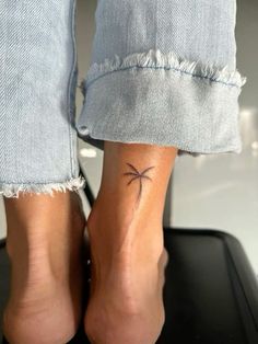 a woman's foot with a small cross tattoo on it