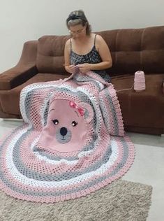 a woman sitting on a couch with a crocheted teddy bear blanket in front of her