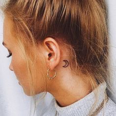 a woman with a small crescent tattoo on her left side of her neck and behind her ear