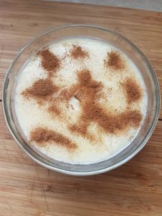 a glass bowl filled with milk and cinnamon on top of a wooden table next to a knife