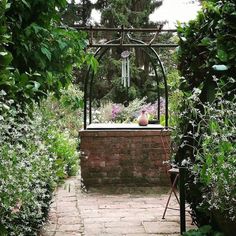 a brick path leads to an outdoor bathtub surrounded by greenery