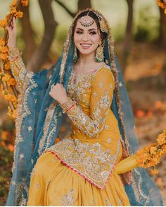 a woman dressed in yellow and blue sitting on a swing with flowers around her neck