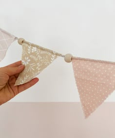 a hand is holding a small triangle shaped bunting banner with white polka dots on it