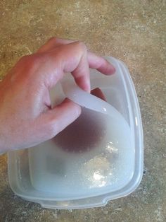 a person's hand reaching for something in a plastic container