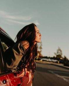 a woman leaning out the window of a red car