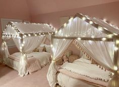 two beds covered in white sheets with lights on them and curtains hanging over the top