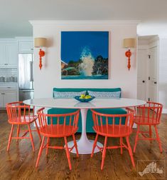 a dining room with orange chairs and a white table surrounded by blue upholstered couches