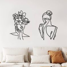 two black and white drawings on the wall of a living room, one with flowers in her hair