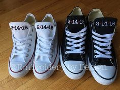 three pairs of white and black tennis shoes with numbers on the laces are sitting on a wooden floor