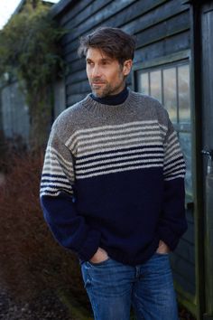 a man standing in front of a building wearing a sweater