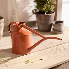 an orange watering can sitting on top of a wooden table