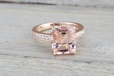 an engagement ring with a pink morganite surrounded by white diamonds on a wooden surface