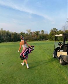 a man walking across a lush green field next to a golf cart