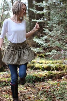 a woman is walking through the woods wearing boots and a skirt with ruffles