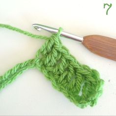 a crochet hook with a wooden handle on top of it next to a piece of yarn