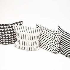 four black and white pillows lined up against a white background, each with different designs