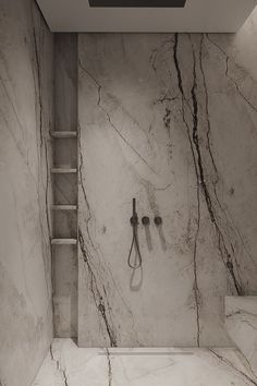 a bathroom with marble walls and flooring, including a shower head mounted to the wall