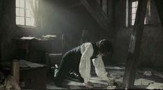 a woman kneeling down on the floor in an old room with papers scattered all over