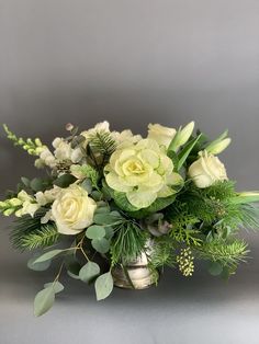 a vase filled with white flowers and greenery