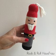 a hand holding a crocheted pipe with a santa clause on it