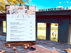 a menu sitting on top of a wooden table next to a sign that says one sale and made in the usa