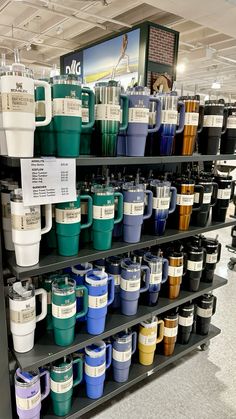 there are many cups on the shelves in this store, all different colors and sizes