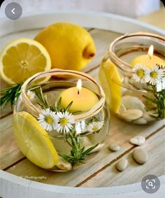 some lemons are sitting in small glass bowls with water and flowers on the side