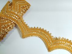 This intricately designed Sari Border Trim is perfect for accentuating your fancy Dupatta, Suits, Lehengas, or Wedding Dress creations. Crafted with precision and passion, this delicate lace boasts a beautiful pale yellow hue, radiating a sense of sophistication and charm. The intricate scallop pattern adorned with shimmering golden sequins adds a luxurious touch, making it a captivating choice for embellishing your special outfits and crafts. Use it in multipurpose projects: ➤Dress border, sare Gold Lehenga With Motifs For Party, Ceremonial Gold Choli With Resham Embroidery, Fitted Yellow Embroidered Fabric For Reception, Yellow Wedding Choli With Motifs, Wedding Yellow Choli With Motifs, Yellow Fitted Embroidered Fabric For Wedding, Fitted Gold Dupatta With Lace Work, Fitted Yellow Embroidered Fabric For Wedding, Festive Gold Lehenga With Lace Work