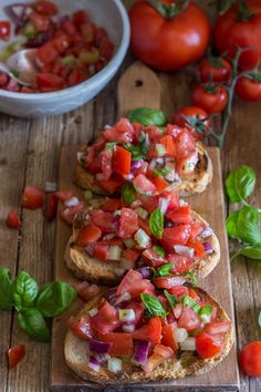 several pieces of bread with tomatoes and onions on them next to a bowl of basil