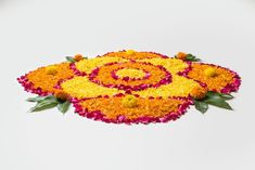 an arrangement of flowers arranged in the shape of a spiral on top of a white surface