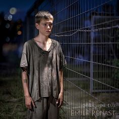 a young man standing next to a fence at night