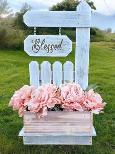 a wooden sign with flowers in it on the grass