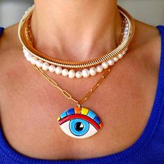 Introduce a splash of color and symbolism to your jewelry collection with our Stainless Steel Chain Necklace featuring a Handmade Ceramic Rainbow Eye Pendant. This striking necklace showcases a beautifully crafted ceramic eye, meticulously handmade and painted with vibrant rainbow colors. Each piece is unique, making it a truly special addition to any wardrobe. The eye pendant, a symbol of protection and positive energy, is delicately suspended from a sleek stainless steel chain. The chain's durable and hypoallergenic properties ensure that this necklace is both stylish and comfortable for everyday wear. This necklace is perfect for adding a bold statement to your look, whether you're dressing up for a special occasion or adding a touch of flair to your casual attire. The combination of th Symbolic Multicolor Necklaces For Gifts, Symbolic Multicolor Necklace For Gift, Artsy White Jewelry For Gifts, Artistic White Necklace For Gift, Colorful Evil Eye Necklace, Artistic White Round Necklace, Evil Eye Necklace Rainbow, Bohemian Multicolor Evil Eye Necklace, Handmade Spiritual Enamel Necklaces