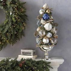 a decorated christmas tree sitting on top of a mantle next to a wreath and other decorations