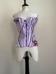 22" waist, double layer, steel boned overbust corset; with in my signature hip panels, and mesh heart cutouts on one side. Features metal spike and faux pearl embellishment, reminiscent of the arrangement of the structure of virus cells (hence the name); applied onto hand died lilac silk dupion, painted to look like butterfly wings. This sample is slightly bigger at the bust, so you may wish to message to double check measurements prior to purchase! This corset is a reworking of an old design, a Fitted Gothic Corset With Sweetheart Neckline, Punk Style Corset With Boned Bodice For Costume Party, Punk Boned Bodice Corset For Costume Party, Fitted Punk Style Corset For Parties, Punk Party Corset With Corset Back, Punk Style Party Corset With Corset Back, Punk Overbust Corset Dress With Boned Bodice, Punk Style Overbust Corset Dress With Boned Bodice, Punk Party Corset With Boned Bodice