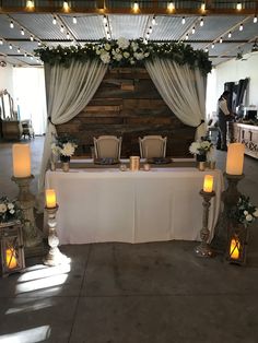 a table set up for a wedding with candles and flowers on the table in front of it