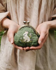 a person holding a small purse with a rabbit on it's front and side