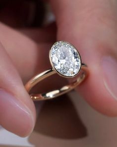 a close up of a person's hand holding a ring with a diamond on it