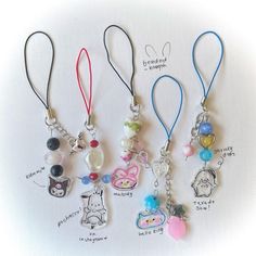 four different keychains with charms attached to them on a white surface, one has an animal and the other has a cat