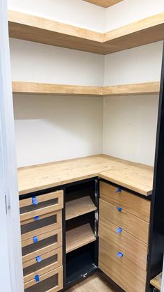 an empty closet with wooden shelves and drawers