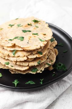 a black plate topped with crackers and parsley on top of a white cloth