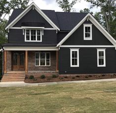 a black house with white trim and two story windows on the second floor is shown