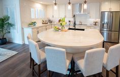 a large kitchen with white cabinets and an island table surrounded by chairs in the center