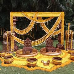 an outdoor wedding setup with yellow flowers and candles on the ground, decorated in gold