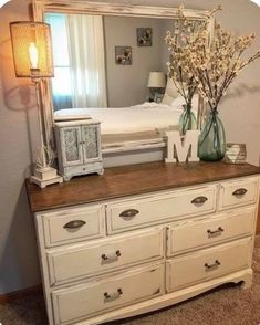 a bedroom with a dresser, mirror and lamp