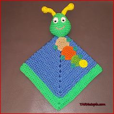 a crocheted green and blue blanket with a smiling bug on it's back